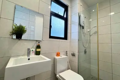 a bathroom with a toilet and a sink and a window at Sunset View Stay at Conezion IOI in Gua Sai
