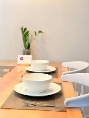 three white bowls on a wooden table with chairs at Iconic Regency Service Residences - Bee's Home in Bayan Lepas