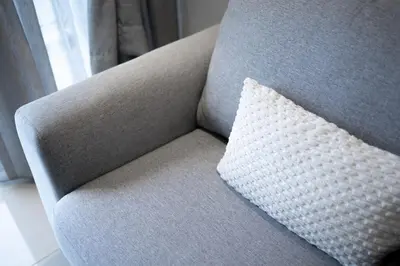 a pillow sitting on a gray chair with a window at IconicRegency #3BR #USM #Queensbay #Airport in Bayan Lepas