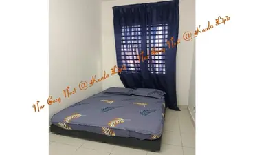 a bedroom with a bed with a blue comforter at Nur Cozy Nest Homestay in Kuala Lipis