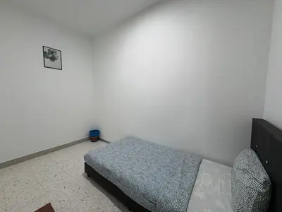 a bedroom with a bed and a white wall at Penang Miami Beach in Batu Ferringhi