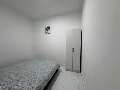 a white bedroom with a bed and a cabinet at Penang Miami Beach in Batu Ferringhi