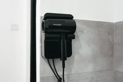 a black hair dryer hanging on a wall at Cameron Centrum CozyNest with Kids Playground Brinchang Clover Home A-1-15A in Brinchang