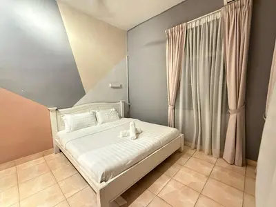 a bedroom with a bed with white sheets and a window at Relax Guest House Taman Merak Jaya Simpang Ampat in Simpang Ampat