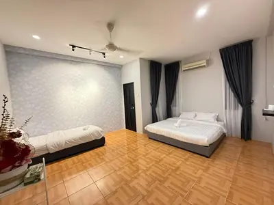 a bedroom with two beds and a wooden floor at Relax Guest House Taman Merak Jaya Simpang Ampat in Simpang Ampat
