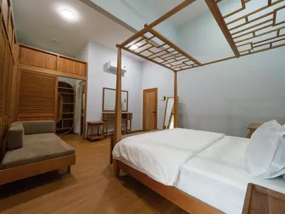 a bedroom with a canopy bed and a chair at D SeBalik Pulau Tropical Boutique Home in Balik Pulau