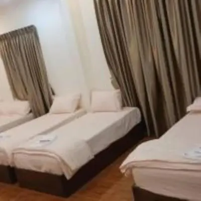 two beds in a room with curtains at mulia homestay in Teluk Intan