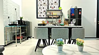 a kitchen with a counter with chairs and flowers on tables at relax familystay Urban suites 3BR-10pax b30 in George Town
