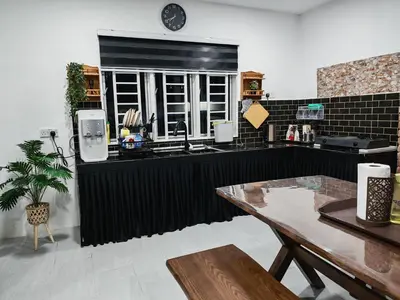 a kitchen with a black counter and a table at Rumah Adaminha, Roomstay with pool Simpang, Taiping in Taiping