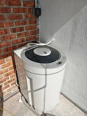 a washing machine sitting next to a brick wall at Rumah Adaminha, Roomstay with pool Simpang, Taiping in Taiping