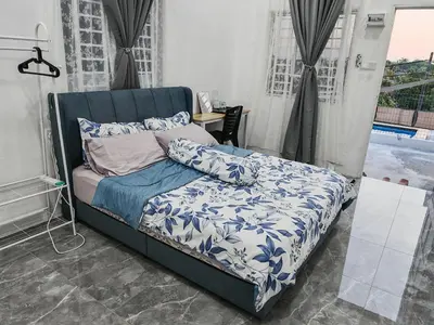 a bedroom with a bed with a blue comforter and pillows at Rumah Adaminha, Roomstay with pool Simpang, Taiping in Taiping