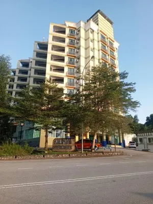 a large building with trees in front of a street at Marina sunset view in Lumut