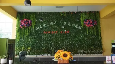 a wall covered in green ivy with flowers in a room at Marina sunset view in Lumut