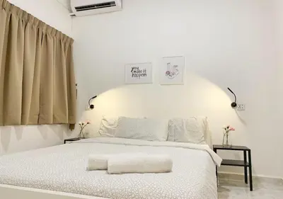 a white bedroom with a bed with a white blanket at Ria Serene Homestay in Sungai Petani