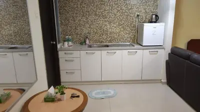 a kitchen with white cabinets and a sink and a table at Home2Stay at Marina Island in Lumut
