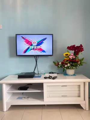 a white desk with a tv on a wall with flowers at AYAAN Fifa Game HOMESTAY At Tanah Rata with Wifi in Tanah Rata
