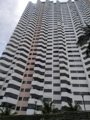 a tall building with palm trees in front of it at sri sayang apartment in Batu Ferringhi