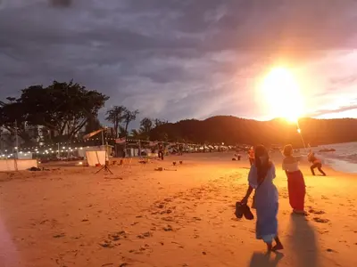 two women standing on a beach at sunset at sri sayang apartment in Batu Ferringhi
