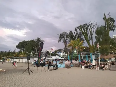 a group of people sitting on a beach at sri sayang apartment in Batu Ferringhi