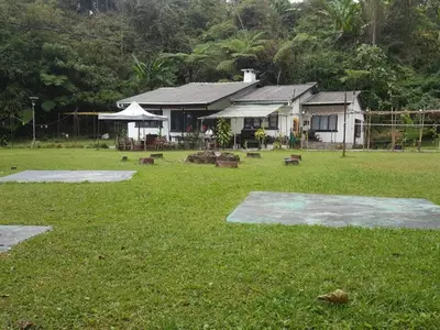 a house with a grass yard with a building at BANGALOW Cameron Highlands in Tanah Rata