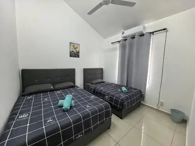 two beds in a bedroom with a blue teddy bear at Padang Serai Taman Ria 61 in Padang Serai