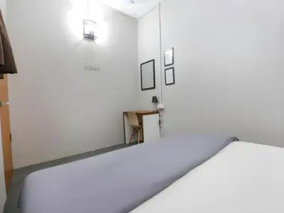 a room with a white wall with a mirror at Bed Station Guest House in Tanah Rata