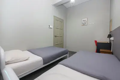 a small room with two beds and a door at Bed Station Guest House in Tanah Rata