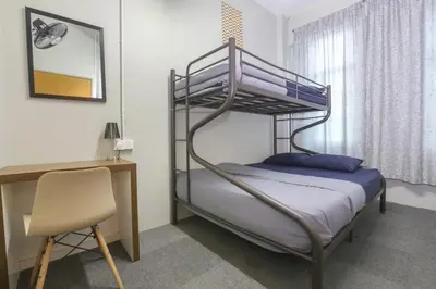 a bedroom with a bunk bed with a desk and a chair at Bed Station Guest House in Tanah Rata