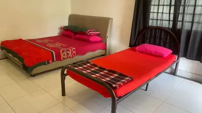 a room with two beds and a table and a chair at Capital O 91189 Chalet Asyuk Maju in Baling