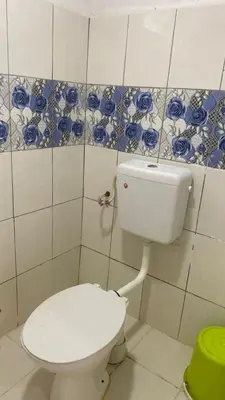 a bathroom with a toilet and blue and white tiles at Capital O 91189 Chalet Asyuk Maju in Baling