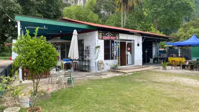 a small white building with a umbrella and a yard at Capital O 91189 Chalet Asyuk Maju in Baling