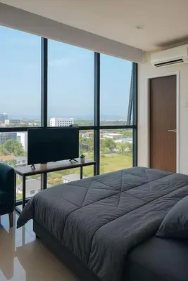 a bedroom with a bed and a desk and large windows at 2 Connecting Room, Kozi Square in Gua Sai