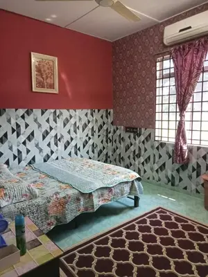 a bedroom with a bed and a red wall at Homestay Mariah in Ipoh