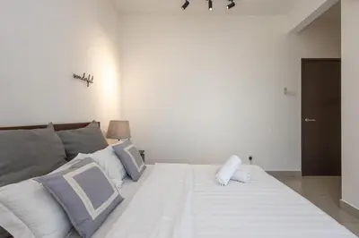 a bedroom with a large white bed with blue and white pillows at Simple Bali l Projector l Netflix l 2 parking in Ipoh