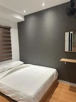 a bedroom with a white bed and a wall at Adik Aisyah black forest luxury cameron homestay in Tanah Rata