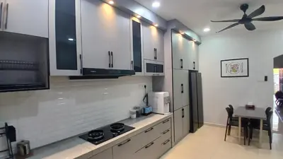 a kitchen with white cabinets and a ceiling fan at Homestay Makyu in Kuala Kangsar