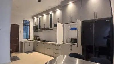a kitchen with white cabinets and black appliances at Homestay Makyu in Kuala Kangsar