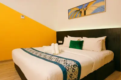 a bedroom with a large bed with yellow walls at Golden Roof Hotel Sunway Ipoh in Ipoh