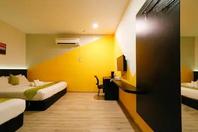 a hotel room with two beds and a yellow wall at Golden Roof Hotel Sunway Ipoh in Ipoh