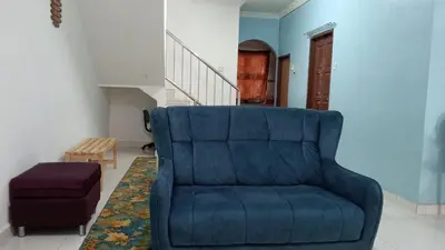 a blue couch in a living room with a staircase at Eyna Homestay in Sitiawan