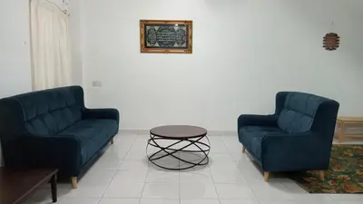 two blue chairs and a table in a living room at Eyna Homestay in Sitiawan
