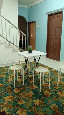 a table and two stools in a room with a staircase at Eyna Homestay in Sitiawan