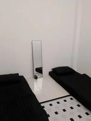 a white room with two beds and a mirror at Nazana Homestay in Batu Gajah