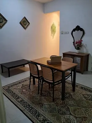 a dining room table with chairs and a laptop on it at Serra Homestay at Apartment Bukit Permata, Lumut in Lumut