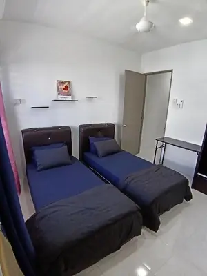 two beds with blue pillows in a room at ShaFA Homestay in Seri Iskandar