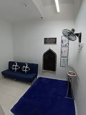 a living room with a blue couch and a blue rug at ShaFA Homestay in Seri Iskandar
