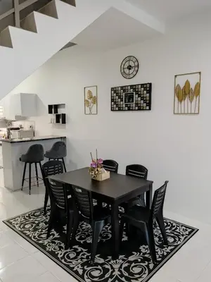 a dining room with a black table and chairs at ShaFA Homestay in Seri Iskandar