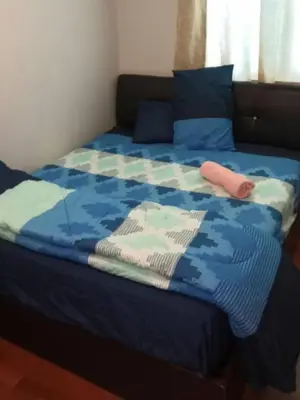 a bed with a blue comforter and a pink object on it at The Haven 3 rooms residence Ipoh in Ipoh