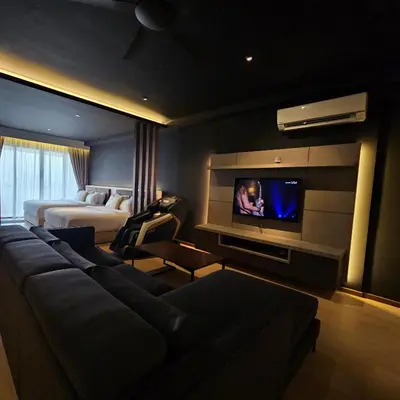 a hotel room with a couch and a tv at Black Martini Premium Suite in Tanjong Tokong