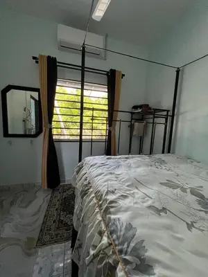 a bedroom with a large bed and a window at Leman's Homestay in Balik Pulau